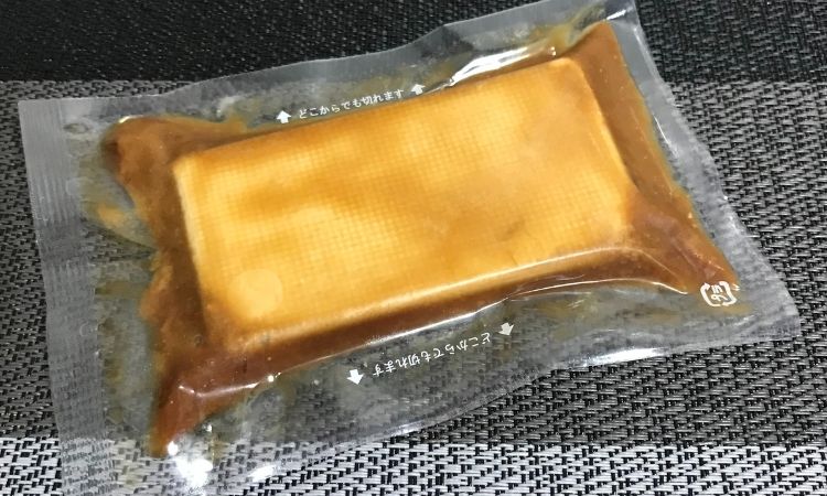 包装を開けて、透明のフィルムに入れられたクリームチーズ。